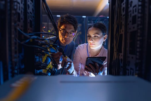 Diverse male and female engineers with digital tablet inspecting the server in computer server room. database server management and maintenance concept