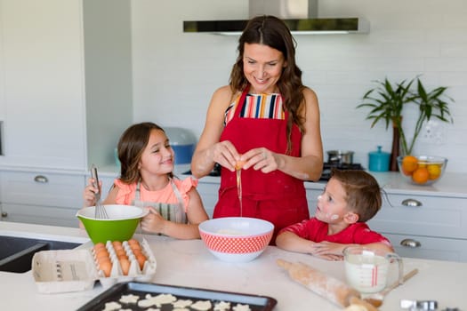 Happy caucasian mother, daughter and son baking together, making cookies in kitchen. family time, having fun together at home.