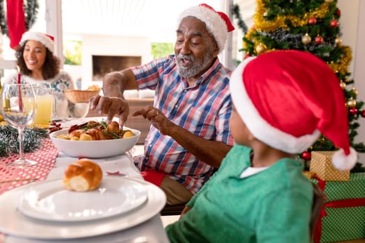 Happy multi generation family wearing santa hats, having christmas meal. family christmas time and festivity together at home.