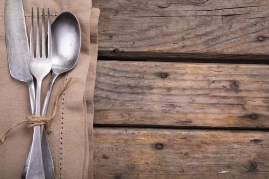 Close up of cutlery set over a napkin on wooden surface. autumn season and restaurant concept