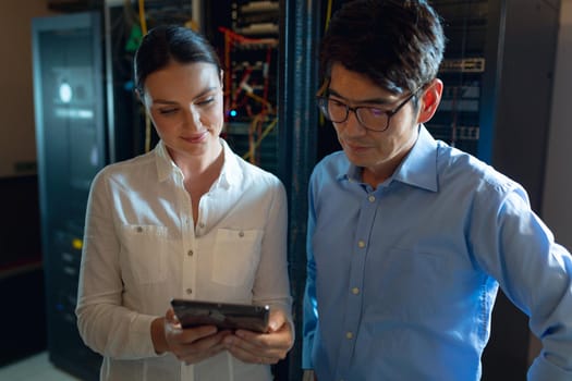 Diverse male and female engineers using digital tablet in computer server room. database server management and maintenance concept