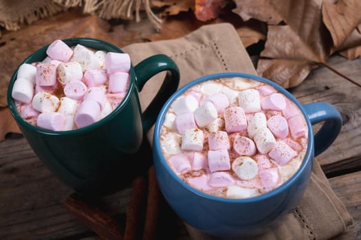 Pink and white marshmallows with hot chocolate drink filled in mugs on table at cafe. hot chocolate drink, cafe culture.
