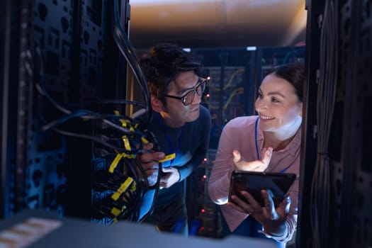 Diverse male and female engineers with digital tablet inspecting the server in computer server room. database server management and maintenance concept