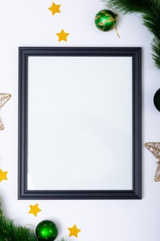 Composition of frame with copy space and fir tree branches with baubles on white background. christmas, tradition and celebration concept.