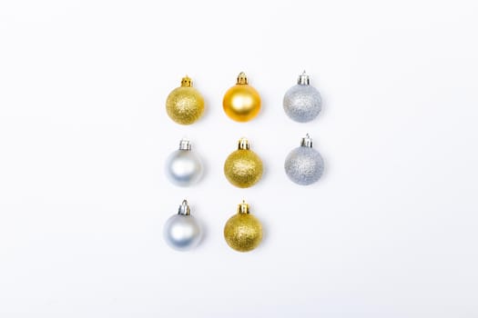 Composition of rows of gold and silver baubles on white background. christmas, tradition and celebration concept.