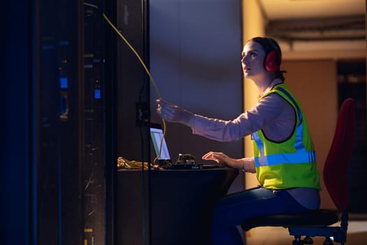 Caucasian female engineer touching a wire in computer server room. database server management and maintenance concept