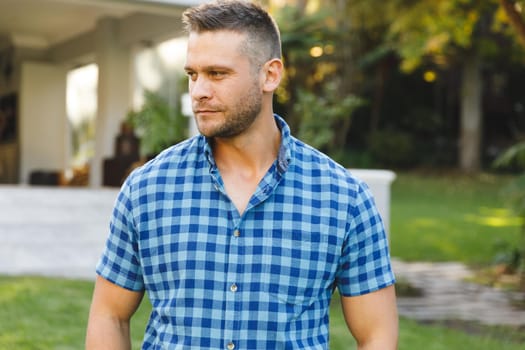 Smiling caucasian man outside house looking away from camera in garden. spending time at home.