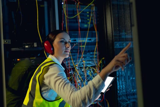 Caucasian female engineer using digital tablet while inspecting in computer server room. database server management and maintenance concept