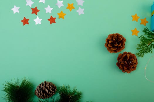Composition of christmas decorations with pine cones and copy space on green background. christmas, tradition and celebration concept.