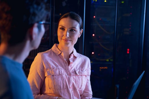 Diverse male and female engineers using laptop in computer server room. database server management and maintenance concept