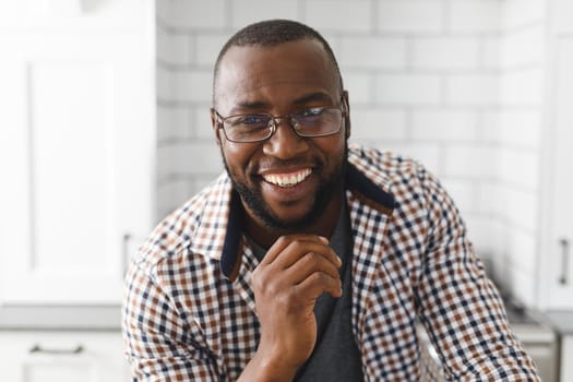 Portrait of happy african american man in kitchen, looking to camera and smiling. spending time at home.