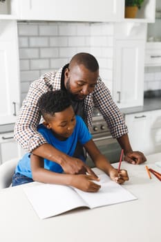 African american father and his son in kitchen, doing homework together. family spending time at home.