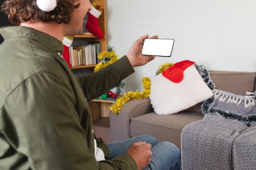 Caucasian disabled man in santa hat using smartphone with copy space at home during christmas. christmas festivity and celebration concept