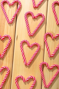 Composition of multiple candy canes in shape of heart on wooden background. christmas, tradition and celebration concept.