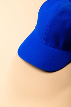 Composition of traditional peaked blue baseball cap on pale brown background. fashion and accessories concept.