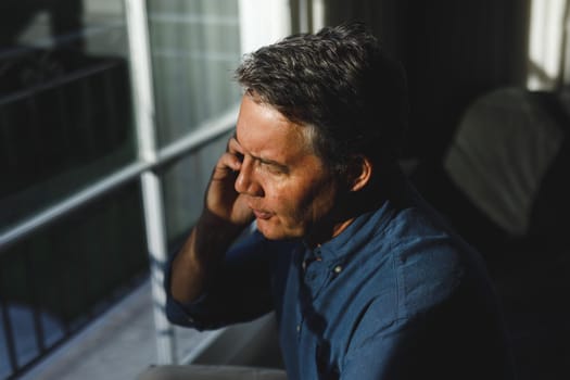 Senior caucasian man in living room sitting on sofa, talking on smartphone. retirement lifestyle, spending time at home with technology.