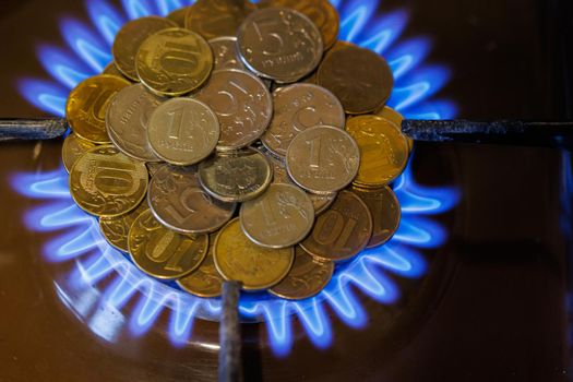 gas stove burner with russian ruble standing vertically on top, burning natural gas with blue flame, gas price in international fuel trade concept