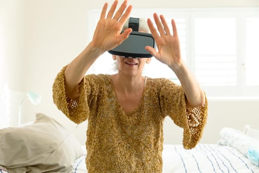 Happy senior caucasian woman wearing vr headset and having fun. active retirement lifestyle at home.