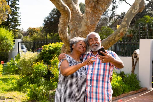 Happy african american senior couple taking selfie in garden. active retirement lifestyle at home and garden.
