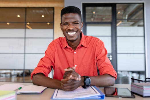 Portrait of cheerful african american businessman in casual with hands clasped at creative office. business and office workplace.