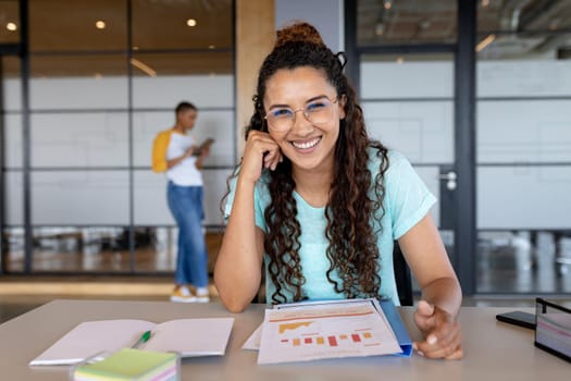 Portrait of smiling young businesswoman in casual sitting with charts at desk in creative office. business and office workplace.