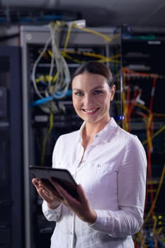 Portrait of caucasian female engineer holding digital tablet smiling in computer server room. database server management and maintenance concept