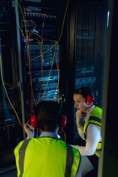 Diverse male and female engineers discussing together while inspecting iin computer server room. database server management and maintenance concept