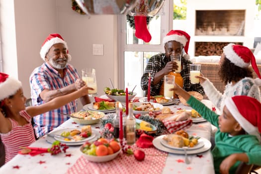 Happy multi generation family wearing santa hats, having christmas meal. family christmas time and festivity together at home.
