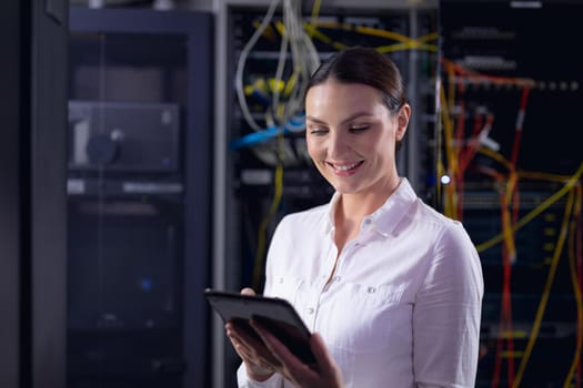 Caucasian female engineer smiling while using digital tablet in computer server room. database server management and maintenance concept