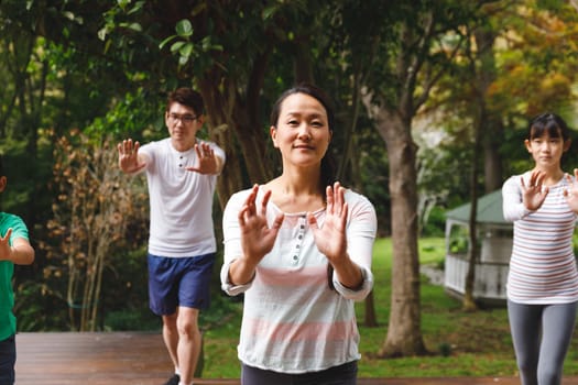 Happy asian parents, son and daughter exercising outdoors, practicing tai chi. family fitness time in garden.