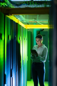 Caucasian female engineer using digital tablet while inspecting in computer server room. database server management and maintenance concept