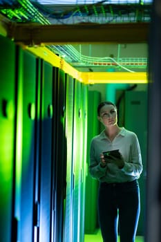 Caucasian female engineer using digital tablet while inspecting in computer server room. database server management and maintenance concept