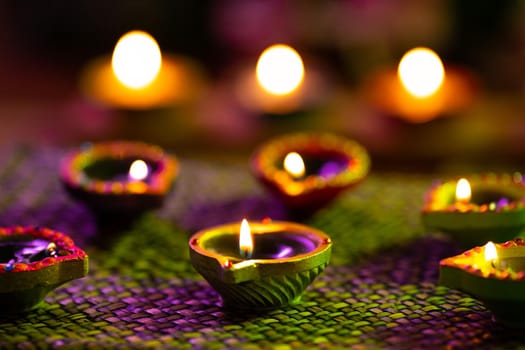 Lit candles in small decorative clay pots burning on woven table cloth. celebration, religion, tradition and ceremony concept.