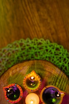 Lit candles in small decorative clay pots and tea light candle burning on round wooden board. celebration, religion, tradition and ceremony concept.