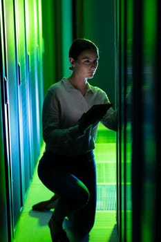 Caucasian female engineer using digital tablet while inspecting in computer server room. database server management and maintenance concept