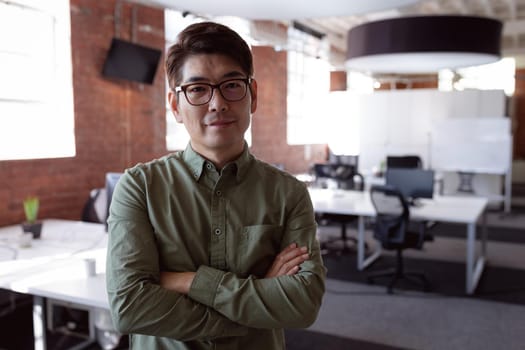 Portrait of serious asian businessman standing in office with arms crossed looking to camera. working in business at a modern office.