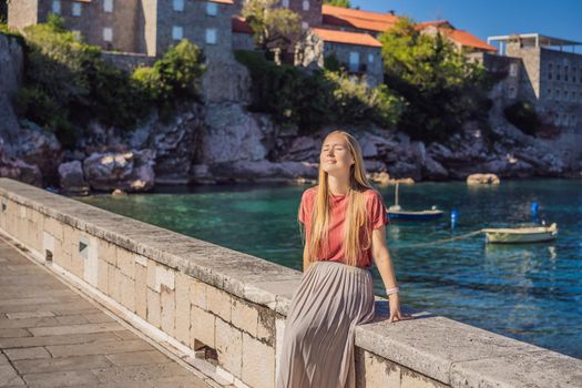 Woman tourist on background of beautiful view of the island of St. Stephen, Sveti Stefan on the Budva Riviera, Budva, Montenegro. Travel to Montenegro concept.