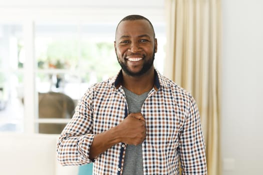 Portrait of african american man smiling and looking at camera in living room talking sign language. communication without words.