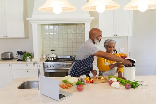 Senior african american couple cooking together in kitchen. retreat, retirement and happy senior lifestyle concept.
