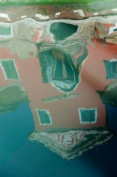 The characteristic colored houses of Burano (Venice) reflected on the water of a canal