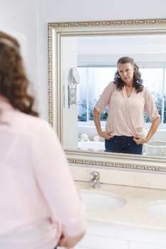 Senior caucasian woman in bathroom, looking at herself in mirror. senior caucasian woman in bathroom, looking at her face in mirror. retirement lifestyle and the aging process.
