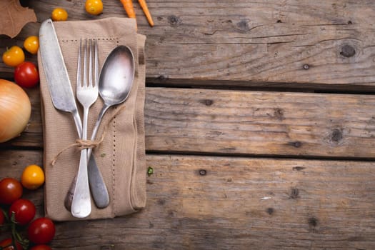 Food ingredients and multiple autumn leaves and cutlery set over a napkin on wooden surface. autumn season and restaurant concept