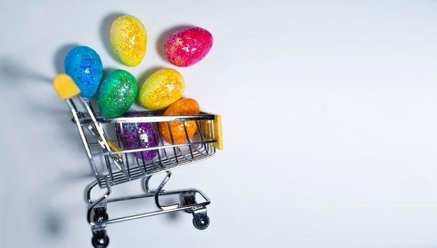 Happy Easter background. Easter colorful eggs in a shopping basket on a white background. Holiday concept. Copy space for text