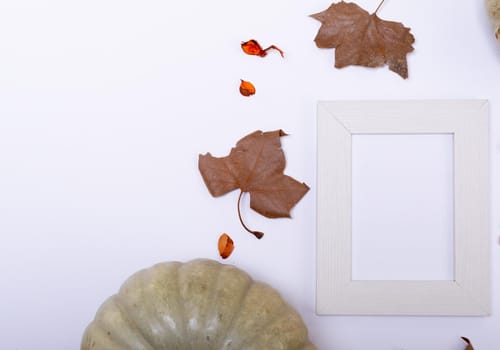 Pumpkin, autumn leaves and empty frame with copy space on white surface. autumn season and halloween concept