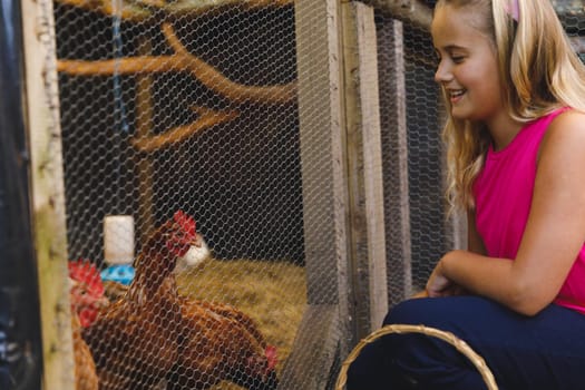 Smiling caucasian girl collecting eggs from hen house in garden. self sufficiency and spending time at home.