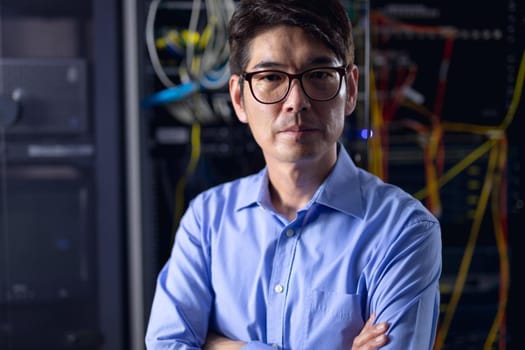 Portrait of asian male engineer with arms crossed in computer server room. database server management and maintenance concept