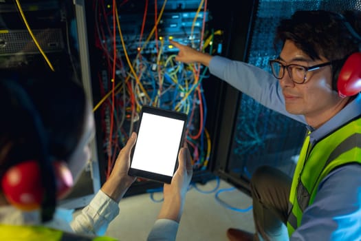 Diverse male and female engineer using digital tablet while inspecting in computer server room. database server management and maintenance concept