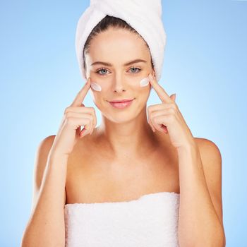 Shot of a young woman doing her skincare routine against a blue background.