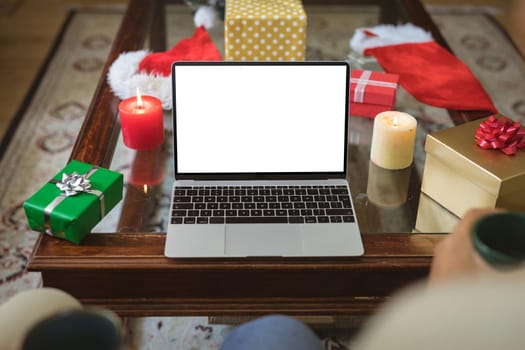 Biracial adult son and senior father making laptop christmas video call. christmas, festivity and communication technology.