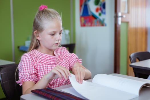 Caucasian schoolgirl sitting at desk in classroom working during lesson. childhood and education at elementary school.